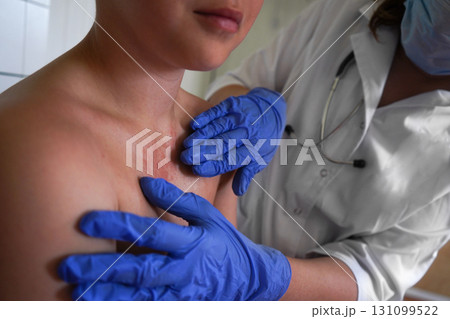 The physician is inspecting the boy's skin for health issues. 131099522