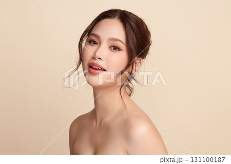 A beautiful young Asian woman with clean, fresh skin against a beige background. Skincare, facial treatment, cosmetology, beauty, and spa. An elegant portrait of an Asian woman. 131100187