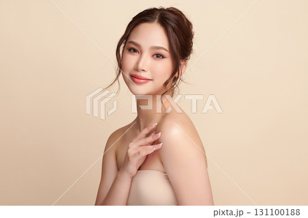 A beautiful young Asian woman with clean, fresh skin against a beige background. Skincare, facial treatment, cosmetology, beauty, and spa. An elegant portrait of an Asian woman. 131100188