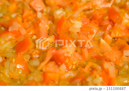 Chopped tomatoes and onions simmering in oil in frying pan cooking sauce. Chopped tomatoes and onions simmering in oil in frying pan cooking sauce. 131100887