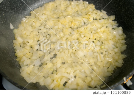Closeup cooking frying chopped onions and garlic in frying pan on kitchen. 131100889