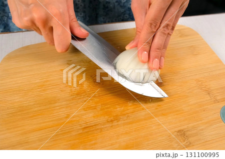 Chef woman hands skillfully chopping white onion on cutting board on kitchen. Chef woman hands skillfully chopping white onion on cutting board on kitchen. 131100995