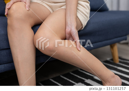 Close-up women holding her calf, indicating leg cramp, muscle strain, or soreness. Concept of muscle fatigue, tired legs, or circulation problems, used in medical or wellness content. 131101257