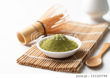 Matcha green tea powder in bowl with wooden spoon and bamboo whisk on white background Matcha green tea powder in bowl with wooden spoon and bamboo whisk on white background 131103789