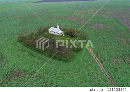 Aerial view of small white chapel in the middle of agricultural field Aerial view of small white chapel in the middle of agricultural field 131103863