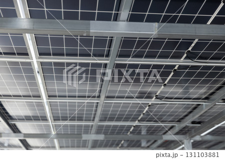 Close-up view of solar panel structure and wiring from underneath. Concept of clean energy, photovoltaic system, renewable power technology, and sustainable infrastructure design. 131103881
