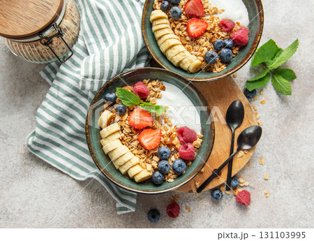 Healthy breakfast bowls with yogurt, granola, banana, and berries 131103995
