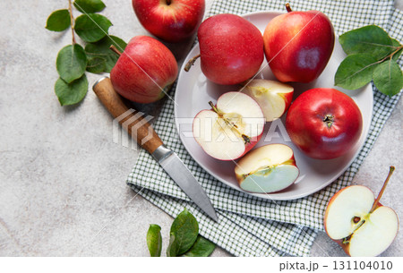 Fresh red apples whole and sliced on white plate with green leaves 131104010