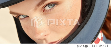 Close-up portrait of a young woman with freckles, intense blue eyes, wearing a blue helmet 131104671