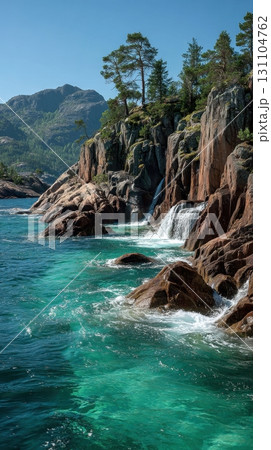 Waterfalls cascade into the turquoise sea along a rocky coastline, where cliffs covered with trees meet the tranquil waters, offering a beautiful view of nature 131104762