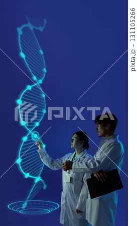 Creative composition. Scientists exploring holographic dna spiral glowing in blue digital projection Creative composition. Scientists exploring holographic dna spiral glowing in blue digital projection 131105266
