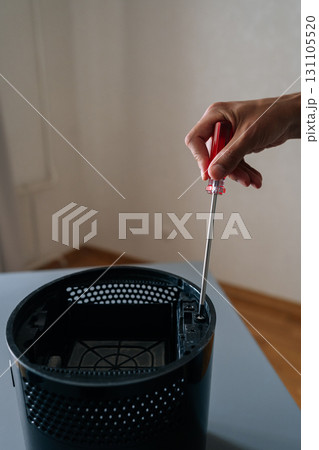 Vertical shot of technician hand using screwdriver to repair or maintain air humidifier, emphasizing importance of regular maintenance for optimal performance. Concept of hygiene and cleanliness. Vertical shot of technician hand using screwdriver to repair or maintain air humidifier, emphasizing importance of regular maintenance for optimal performance. Concept of hygiene and cleanliness. 131105520