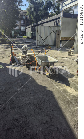 A construction site. A wheelbarrow and shovel, piles of sand and gravel nearby. 131106531