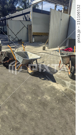 A construction site. A wheelbarrow and shovel, piles of sand and gravel nearby. A construction site. A wheelbarrow and shovel, piles of sand and gravel nearby. 131106532