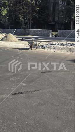 A construction site. A wheelbarrow and shovel, piles of sand and gravel nearby. A construction site. A wheelbarrow and shovel, piles of sand and gravel nearby. 131106533