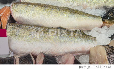 Frozen sea and freshwater fish on a supermarket shelf Sliced and whole Seafood 131106558