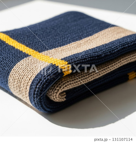Folded Blue Beige and Yellow Striped Blanket on White Surface Folded Blue Beige and Yellow Striped Blanket on White Surface 131107114
