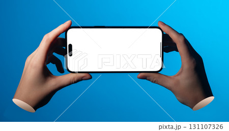 Lodz Poland May 01 2025 Hands holding smartphone in horizontal position. Blank screen mockup placed 131107326