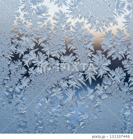 Icy Window with Frost Patterns Against Blurred Sky Background in Winter Season 131107448