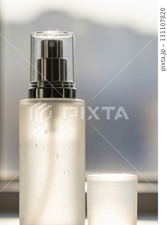 Frosted Glass Spray Bottle with Clear Cap and Water Droplets on Soft Focus Background 131107820