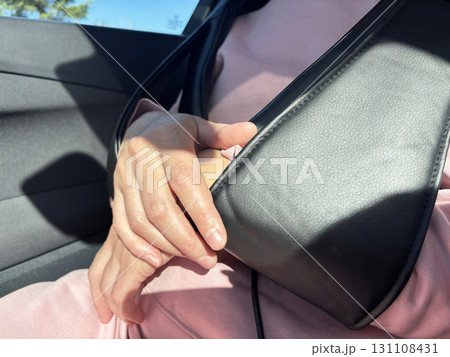 A woman enjoys a massage with an electric massager in a car. Relaxation during a long drive or trip, portable massage device for neck and shoulders, health and wellness lifestyle 131108431