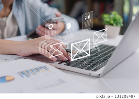 Email communication and digital marketing concept.businesswoman typing on laptop with email and document.Online office workflow with data report charts, digital files, and wireless messaging 131108497