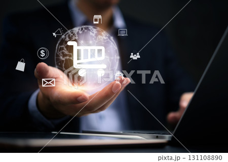 Businessperson holding a glowing globe with various e-commerce symbols like a shopping cart, house, and laptop. Ideal for representing global online shopping and digital transactions. Businessperson holding a glowing globe with various e-commerce symbols like a shopping cart, house, and laptop. Ideal for representing global online shopping and digital transactions. 131108890