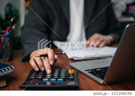 Business person analyzing financial data with paperwork and laptop, showing calculation, expense management, and financial reporting. accounting, budgeting, and tax planning Business person analyzing financial data with paperwork and laptop, showing calculation, expense management, and financial reporting. accounting, budgeting, and tax planning 131109249