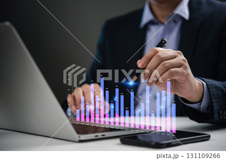 Businessman analyzing financial statistics on laptop with digital bar chart, business growth, economic trends, data analysis, and investment planning. KPI metrics Businessman analyzing financial statistics on laptop with digital bar chart, business growth, economic trends, data analysis, and investment planning. KPI metrics 131109266