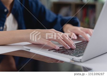 Close-up of hands typing on a laptop, showing the fingers in focus on a modern keyboard. Great for illustrating technology, work from home, and online business concepts. Close-up of hands typing on a laptop, showing the fingers in focus on a modern keyboard. Great for illustrating technology, work from home, and online business concepts. 131109287
