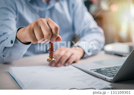 close-up shot of a hand applying a legal stamp to a contract in an office, signifying the final approval and authentication of important business documents. 131109301