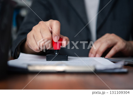 Businessman stamping document to approve official contract, concept of legal authorization and business validation. financial, banking, or investment documents at his desk official paperwork. 131109304