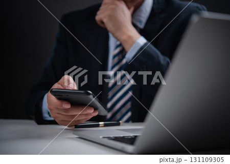 Corporate leader holding phone with pen and laptop, great for concepts of business thinking, fintech, and remote leadership. Corporate leader holding phone with pen and laptop, great for concepts of business thinking, fintech, and remote leadership. 131109305