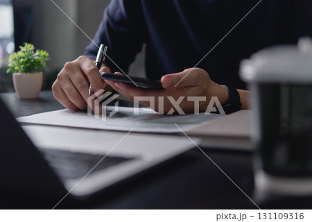 Financial analysis with paper document and smartphone in hand, modern business planning, online data access and remote work flexibility. Financial analysis with paper document and smartphone in hand, modern business planning, online data access and remote work flexibility. 131109316