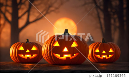 Brightly lit jack-o'-lanterns glowing at sunset in an autumn park setting 131109363