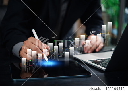 businessman analyzing financial data and growth trends on a tablet with digital graphs and charts, working on a laptop in a modern office. businessman analyzing financial data and growth trends on a tablet with digital graphs and charts, working on a laptop in a modern office. 131109512