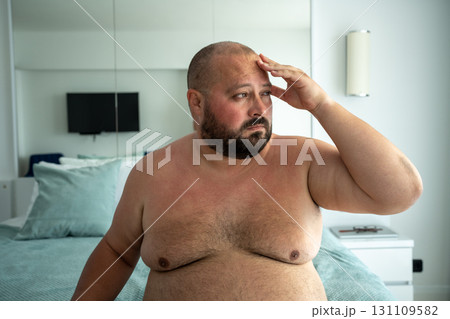 Portrait of overweight naked bearded man in air-conditioned room escaping from heat in hotel. Portrait of overweight naked bearded man in air-conditioned room escaping from heat in hotel. 131109582