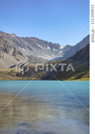 Idyllic summer landscape with hiking trail in the mountains with beautiful fresh green mountain pastures, lake with reflection. Alai ridge mountains 131109915