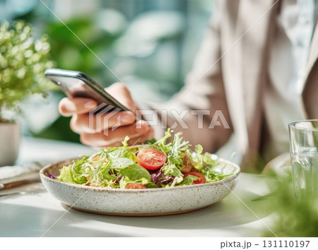 Woman using phone having healthy salad lunch 131110197