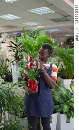 Young florist presenting guzmania plant in flower shop 131110552