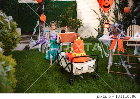 Children celebrating Halloween pulling wagon in decorated backyard Children celebrating Halloween pulling wagon in decorated backyard 131110590
