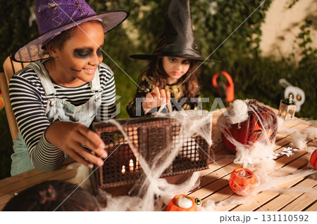 Two young girls preparing Halloween decorations at home in the garden Two young girls preparing Halloween decorations at home in the garden 131110592