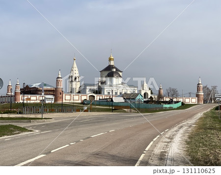 Orthodox monastery with bell towers and church under cloudy sky, road leading to entrance 131110625