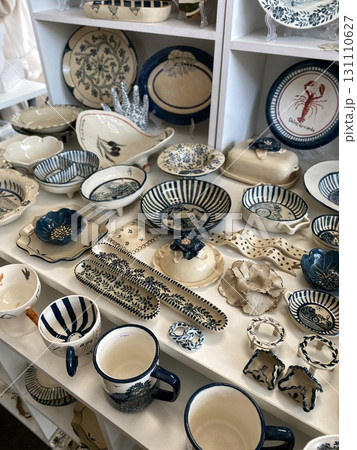 Assorted blue and white ceramic dishware displayed on white shelves in a store setting 131110627