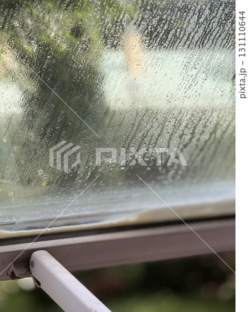 Raindrops on window creating a textured background with blurred green foliage in the distance Raindrops on window creating a textured background with blurred green foliage in the distance 131110644