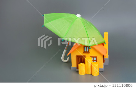 Miniature model of a house with coins under a green umbrella. Property and family insurance concept. Safety life. Care of finance, wealth and savings Miniature model of a house with coins under a green umbrella. Property and family insurance concept. Safety life. Care of finance, wealth and savings 131110806