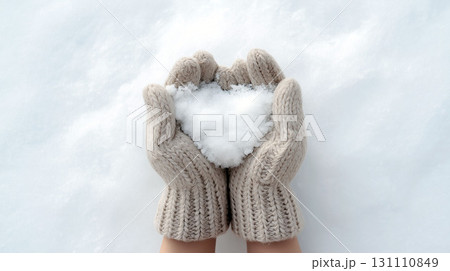 Hands in woolen gloves holding heart-shaped snow on a soft snowy background 131110849