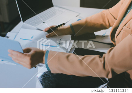 Close-up of businessman's hands making notes, mobiles, chart, desk, office Close-up of businessman's hands making notes, mobiles, chart, desk, office 131111334
