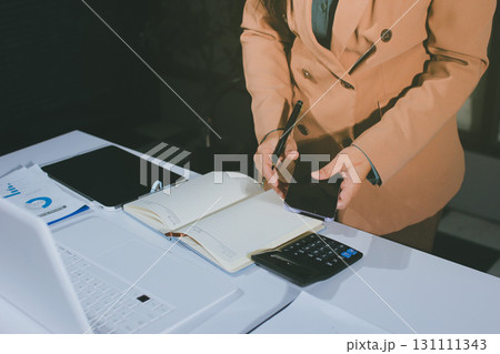 Close-up of businessman's hands making notes, mobiles, chart, desk, office Close-up of businessman's hands making notes, mobiles, chart, desk, office 131111343