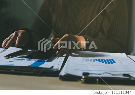 Close-up of businessman's hands making notes, mobiles, chart, desk, office Close-up of businessman's hands making notes, mobiles, chart, desk, office 131111344